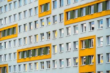 Patterned residential facade with alternating yellow and green window accents