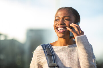 Joyful African American young woman talking on phone outdoors