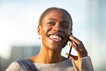 Close-up of joyful African American woman on phone outdoors