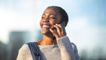 Laughing African American woman in sweater having phone conversation