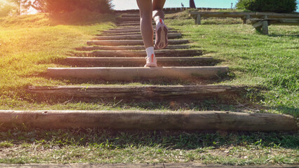 Close up of legs running up stairs in a park at sunset, demonstrating fitness and determination
