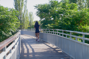 Sporty woman running on a bridge in a park during summer, enjoying her outdoor workout