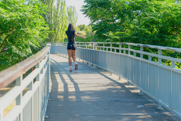 Young woman running alone on a bridge in a park during a sunny day