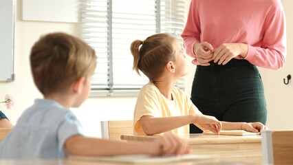 Beautiful teacher explaining test while caucasian boy doing classwork and listening explanation....