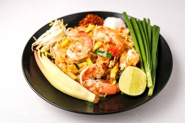 Stir fried thai noodles with shrimps ,Pad Thai in black plate on white background