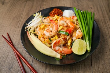 Stir fried thai noodles with shrimps ,Pad Thai in black plate on wooden  background