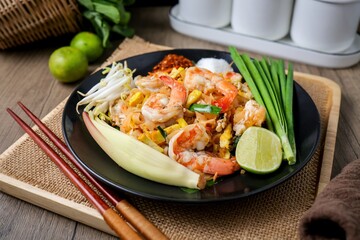 Stir fried thai noodles with shrimps ,Pad Thai in black plate on wooden  background