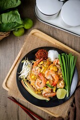 Stir fried thai noodles with shrimps ,Pad Thai in black plate on wooden  background