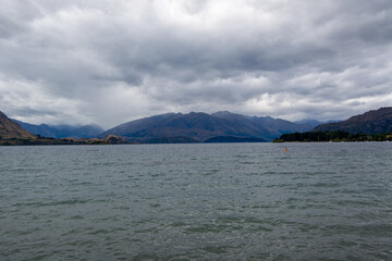 Serene Lake Surrounded by Mountains Under Cloudy Sky
