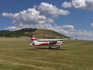  A small red and white propeller airplane on a grassy airfield, concept of aviation, flight...
