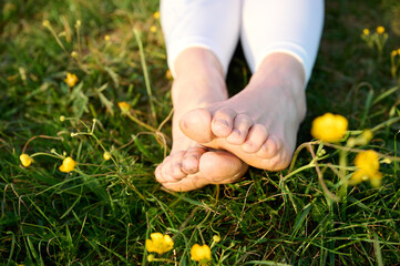 Woman legs on the green grass. Close up view of feet on the grass. The female's bare feet on the lawn. resting girl in the sun. The concept of relaxation and a connection with nature