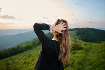 Close-up portrait of a young woman standing on a mountain at sunrise. Peaceful morning in nature,...