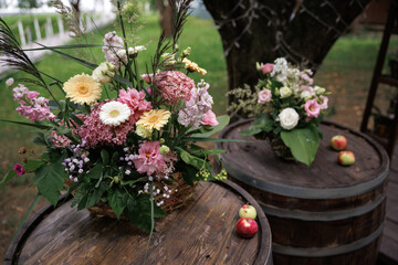 Rustic floral arrangements elegantly placed on wooden barrels with scattered apples create a...
