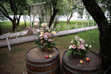 Rustic floral arrangements elegantly placed on wooden barrels with scattered apples create a...