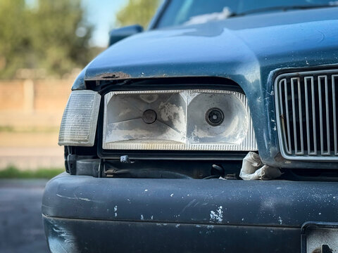 Front of blue color car damaged and broken by accident on the road. Close-up of the headlights of an accident that has been damaged severely. Broken headlight of a car, after an crash.