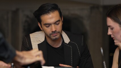 Portrait of focus smart businessman looking at special drink list menu with couple while waiter...