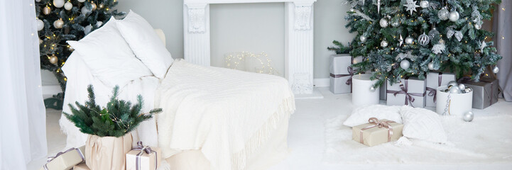 Bright interior with a false fireplace decorated for Christmas. Christmas trees with garlands, balloons and lights.