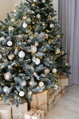 A large Christmas tree in the living room, decorated with garlands and light balloons. Bright Christmas interior.