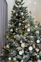 A large Christmas tree in the living room, decorated with garlands and light balloons. Bright Christmas interior.