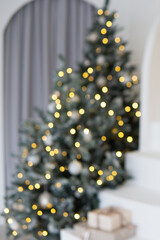 A large Christmas tree in the living room, decorated with garlands and light balloons. Bright Christmas interior with a white staircase.