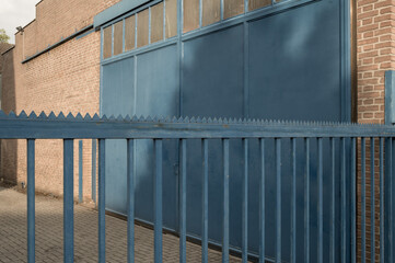 Blue metal fence protecting industrial building with closed gate