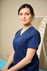 Portrait of female doctor in medical attire sitting on the coach. Vertical orientation.