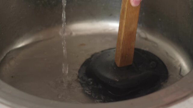 clearing clogged sink with plunger close-up, plumber clearing clogged sink in kitchen