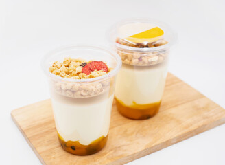 Passion Fruit Greek Yogurt Parfaits with Granola and Dried Fruit in cups on wooden board side view of light dessert