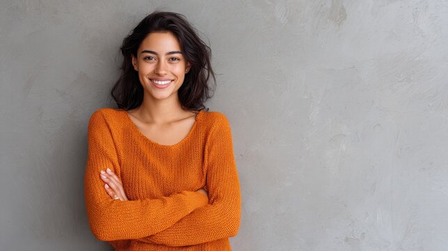 Portrait of a young latin woman with pleasant smile and crossed arms isolated on grey wall with copy space. Beautiful girl with folded arms looking at camera against grey wall. Cheerful hispanic woma - Powered by Adobe