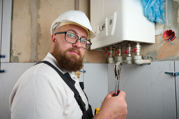 Plumber Install a Boiler. Professional engineer installing gas boiler at home and checking the connections and pipes of the domestic heating system. Boiler Installation Service adjusting 