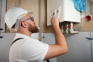 Plumber Install a Boiler. Professional engineer installing gas boiler at home and checking the...