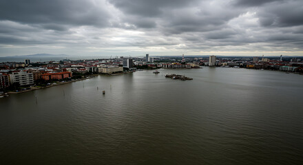 Obraz premium Cloudy Waterfront Cityscape with Buildings and Flooded River