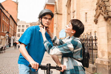 Young couple adjusts bicycle helmet in historic city center during sunny afternoon, showcasing urban lifestyle and safety awareness