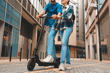 Young couple riding an electric scooter together in a modern urban setting during the daytime
