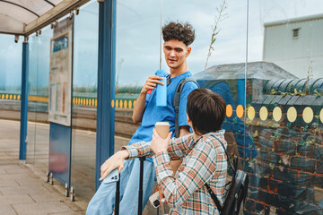 Friends chatting at a bus stop enjoying drinks and connecting on a sunny day in an urban area