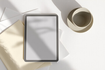 A 3D flat lay captures a minimalist workspace with a generic tablet, a cup, and various papers, all under natural light with prominent shadows.