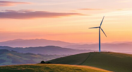 Obraz premium A lone wind turbine stands on a grassy hill at sunset