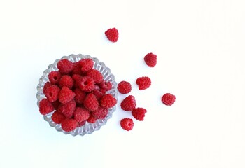 Ripe raspberries in a glass bowl on a white background