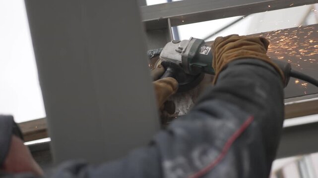 Rotating angle grinder slices through steel with loud confident motion. Focused worker firmly guides path with controlled precise pressure