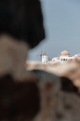Dreamy view of Oia’s windmill and domes through volcanic rocks, Santorini