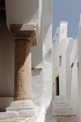 A narrow alleyway in Sifnos, Cyclades, showcasing bright whitewashed walls, soft shadows, and an...