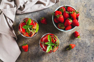 Summer detox water with strawberries and basil in glasses on the table top view