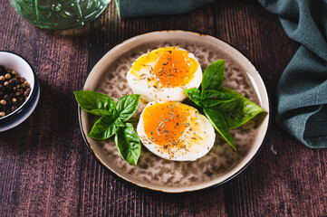 Spicy soft-boiled egg halves and basil on a plate on a table