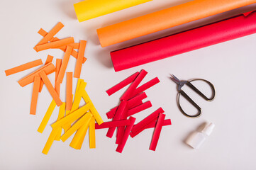 Strips of colored paper, scissors and glue to make paper garlands top view