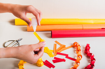 A girl's hands pour glue onto a strip of paper to make a paper chain