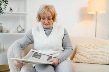 age and people concept, happy senior woman reading newspaper at home