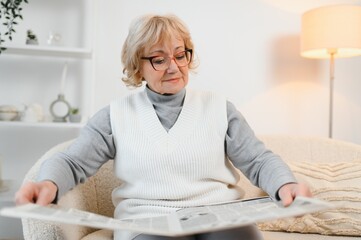 age and people concept, happy senior woman reading newspaper at home