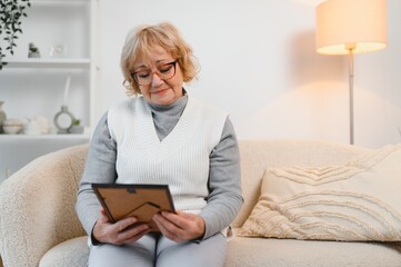 Sad old elderly with depression looks at photograph of her family with nostalgia,remembrance,...