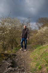 Man with beard walks on rocky path through forest