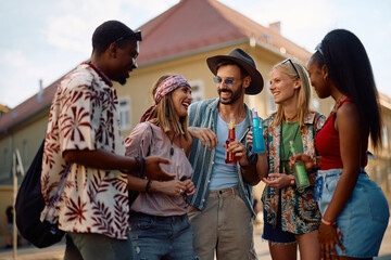Cheerful festival goers talking on the street while attending music concert in summer.